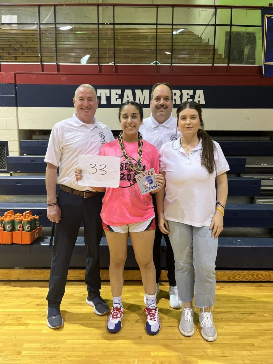 Senior Hannah Tamu '25 celebrates her record tie with her coach and parents after the game. 